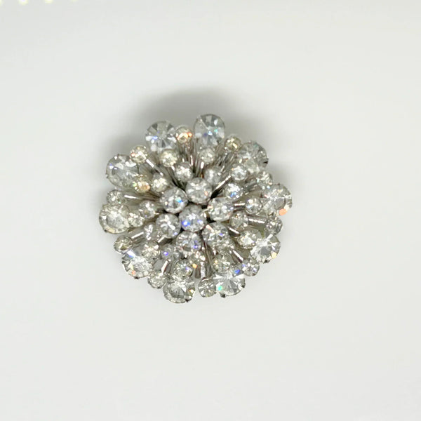 This extraordinary vintage rhinestone brooch features several layers of brilliant, round, sparking stones of varying sizes, measuring 2" across. The back of the brooch is stunning, showcasing exquisite metalwork and reflecting its excellent condition.