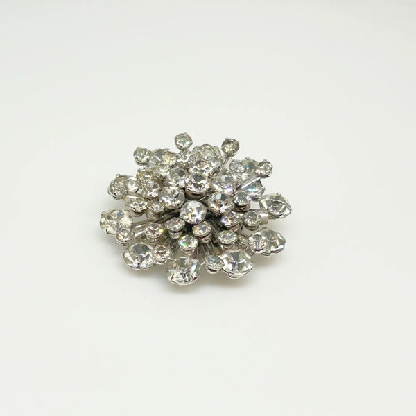 This extraordinary vintage rhinestone brooch features several layers of brilliant, round, sparking stones of varying sizes, measuring 2" across. The back of the brooch is stunning, showcasing exquisite metalwork and reflecting its excellent condition.