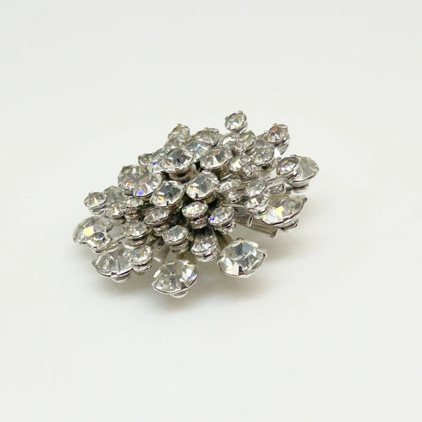 This extraordinary vintage rhinestone brooch features several layers of brilliant, round, sparking stones of varying sizes, measuring 2" across. The back of the brooch is stunning, showcasing exquisite metalwork and reflecting its excellent condition.