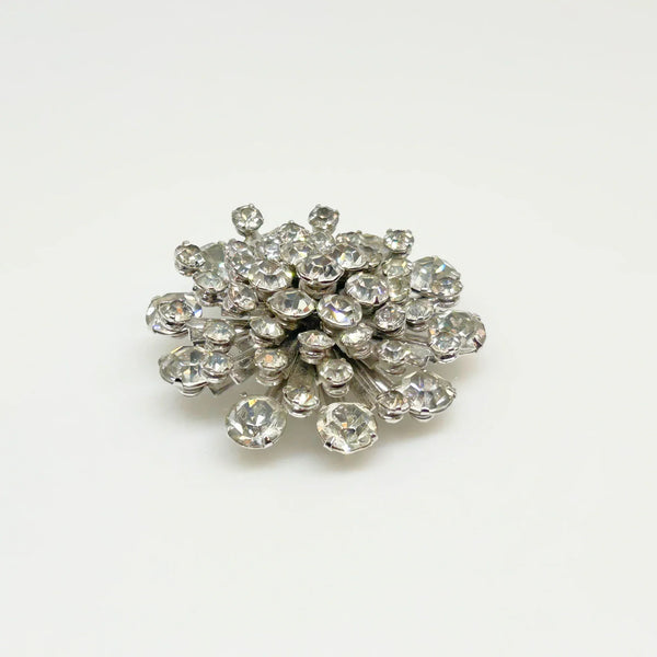 This extraordinary vintage rhinestone brooch features several layers of brilliant, round, sparking stones of varying sizes, measuring 2" across. The back of the brooch is stunning, showcasing exquisite metalwork and reflecting its excellent condition.