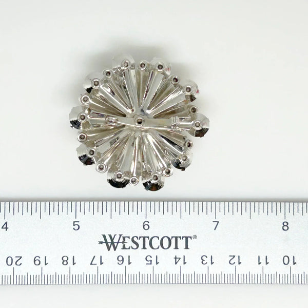This extraordinary vintage rhinestone brooch features several layers of brilliant, round, sparking stones of varying sizes, measuring 2" across. The back of the brooch is stunning, showcasing exquisite metalwork and reflecting its excellent condition.