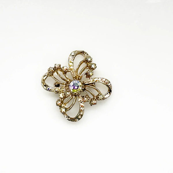 This is a three dimensional vintage ribbon brooch featuring clear rhinestones and a central aurora borealis (AB) gemstone, designed in an abstract floral or bow shape. 