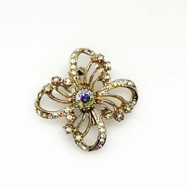 This is a three dimensional vintage ribbon brooch featuring clear rhinestones and a central aurora borealis (AB) gemstone, designed in an abstract floral or bow shape. 
