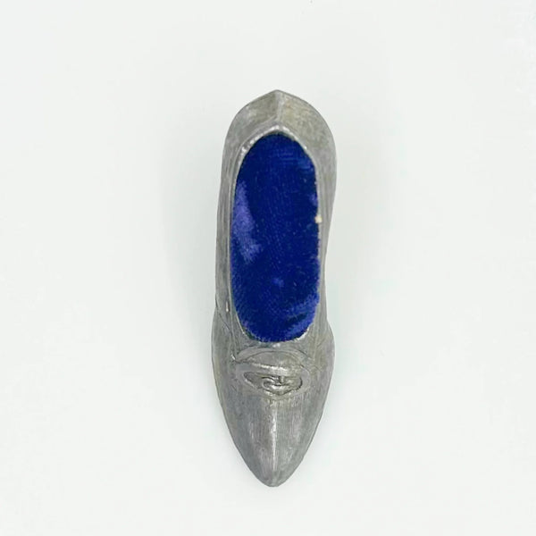 This dainty vintage pincushion is just the thing the add a unique touch to your surroundings. It is made of pewter in the shape of a shoe, with a classic loafer type detail at the toe. It has a .75" kitten heel, and the insole is filled with dark blue, midnight velvet.