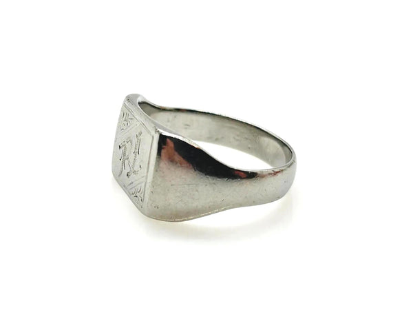 A silver-toned signet ring with a square face and engraved lettering, shown on a plain white background.