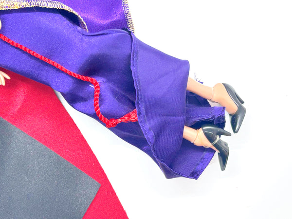 A vintage-style Evil Queen doll with a gold crown, purple gown, and red cape, photographed against a plain white background.
