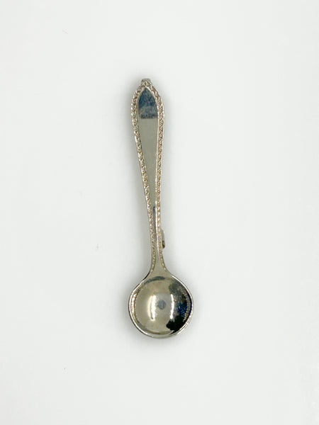 A vintage-style silver-toned metal pin with a spoon-shaped head and a long, narrow pin stem, photographed on a plain white background.