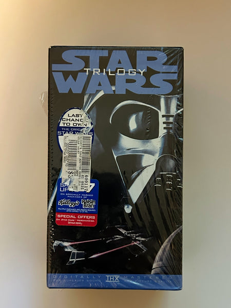Front view of the 1995 Star Wars Trilogy Faces Edition 3-tape VHS box set in partial shrinkwrap featuring Darth Vader artwork and vintage promotional stickers