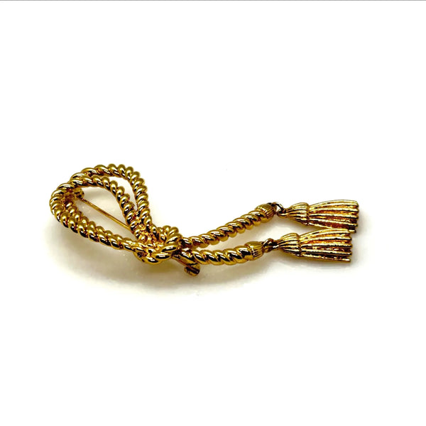 This dramatic Avon gold-tone brooch, a delightful piece from the 1980s, showcases a captivating knotted rope design. The brooch features dangling tassels, adding a touch of vintage charm.