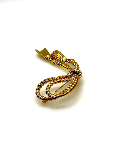 This dramatic Avon gold-tone brooch, a delightful piece from the 1980s, showcases a captivating knotted rope design. The brooch features dangling tassels, adding a touch of vintage charm.