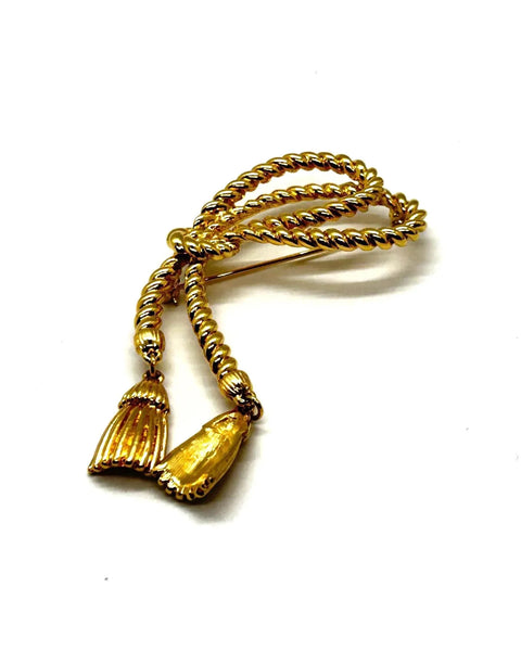 This dramatic Avon gold-tone brooch, a delightful piece from the 1980s, showcases a captivating knotted rope design. The brooch features dangling tassels, adding a touch of vintage charm.
