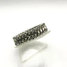 Three-row vintage rhinestone expansion bracelet with small, faceted stones set in a silvertone accordion-style stretch band, shown resting at an angle on a clear display stand against a white background