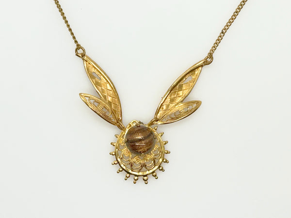 A gold pendant necklace featuring a stylized winged design with a textured oval brown center stone, photographed against a plain white background.