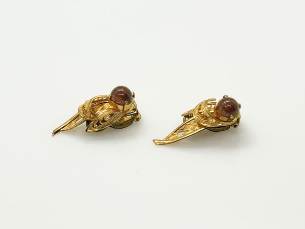 A pair of vintage gold-toned winged earrings with round brown cabochon gemstones, displayed on a clean white background.
