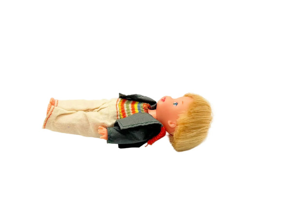 Vintage boy doll with blonde hair, rainbow sweater, and black jacket, collectible toy