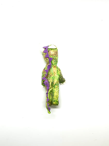 A vintage 2003 Mattel Kelly Club 4-inch Tommy doll dressed in a green dragon Halloween costume with a purple chest patch and purple spiked tail. The mini pocket doll has blonde hair and blue eyes, photographed standing against a solid white background