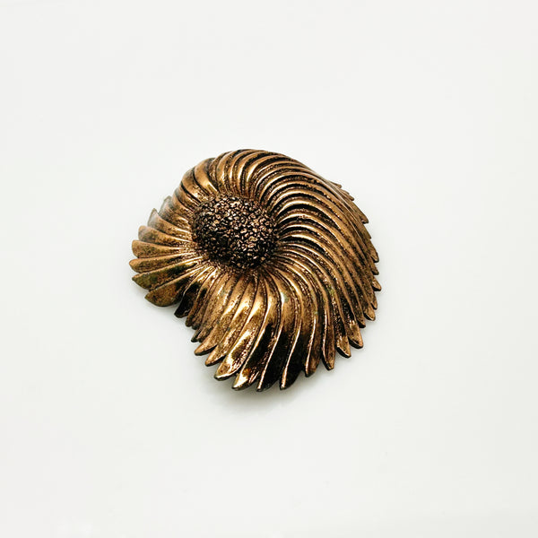 Vintage Tortolani copper-toned shell brooch featuring a textured, swirling modernist design reminiscent of a nautilus shell with a central cluster of dense, nugget-like details against a solid white background