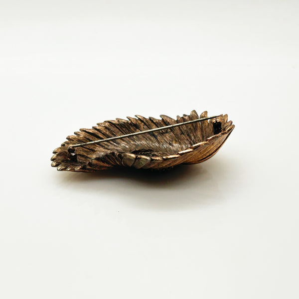 Vintage Tortolani copper-toned shell brooch featuring a textured, swirling modernist design reminiscent of a nautilus shell with a central cluster of dense, nugget-like details against a solid white background