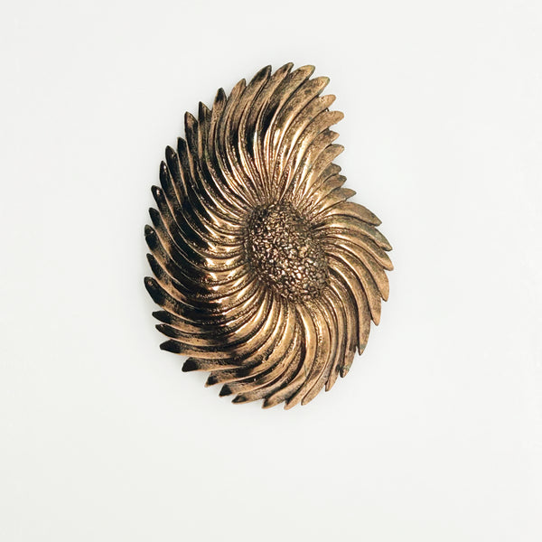 Vintage Tortolani copper-toned shell brooch featuring a textured, swirling modernist design reminiscent of a nautilus shell with a central cluster of dense, nugget-like details against a solid white background