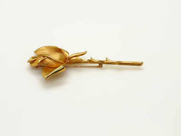 Vintage Crown Trifari gold-tone long-stem rose brooch featuring a detailed, textured matte rosebud on a thorny gold stem against a clean white background.