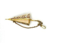 Vintage Spanish Damascene umbrella brooch with gold-tone filigree canopy panels, detailed red and black enamel patterns, a triangular mother of pearl inlay, and a dangling gold chain with a teardrop faux pearl charm against a plain white background