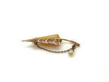 Vintage Spanish Damascene umbrella brooch with gold-tone filigree canopy panels, detailed red and black enamel patterns, a triangular mother of pearl inlay, and a dangling gold chain with a teardrop faux pearl charm against a plain white background