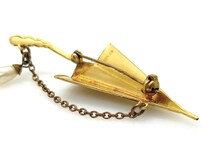 Vintage Spanish Damascene umbrella brooch with gold-tone filigree canopy panels, detailed red and black enamel patterns, a triangular mother of pearl inlay, and a dangling gold chain with a teardrop faux pearl charm against a plain white background