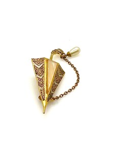 Vintage Spanish Damascene umbrella brooch with gold-tone filigree canopy panels, detailed red and black enamel patterns, a triangular mother of pearl inlay, and a dangling gold chain with a teardrop faux pearl charm against a plain white background