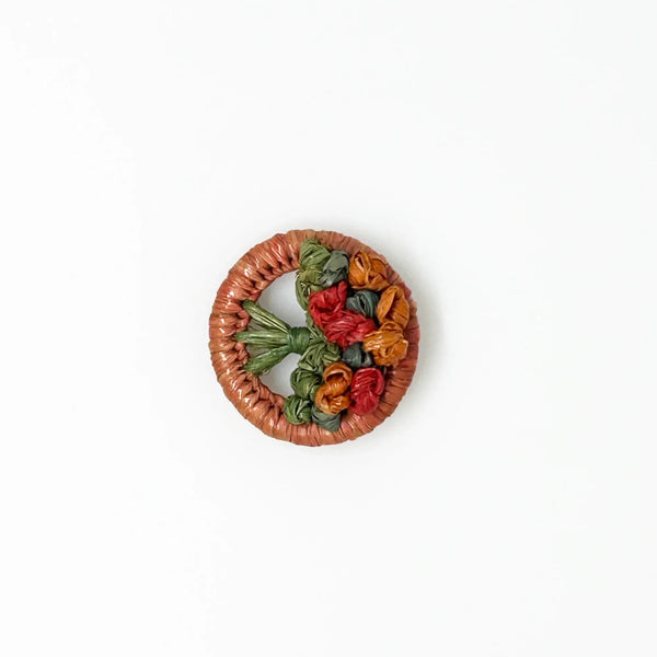 This beautiful antique brooch, likely dating back to the early 1900s, is quite rare. It showcases a charming design with colored straw wrapped around a circular frame. Inside, you'll find a delicate, hand-crafted tree or bouquet made from fine threads.