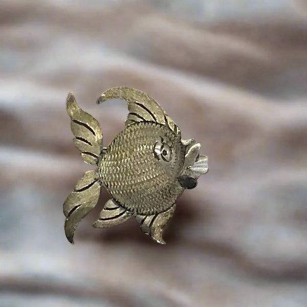 This is a whimsical brooch in the shape of a fish. The detailing on the scales and fins is particularly nice. It measures 1.25” across. Add a touch of charm to any outfit with our Vintage Mexican Silver Fish Brooch. You'll love the intricate detailing on the scales and fins, giving it a unique and whimsical touch. At 1.25" across, it's the perfect size for everyday wear.