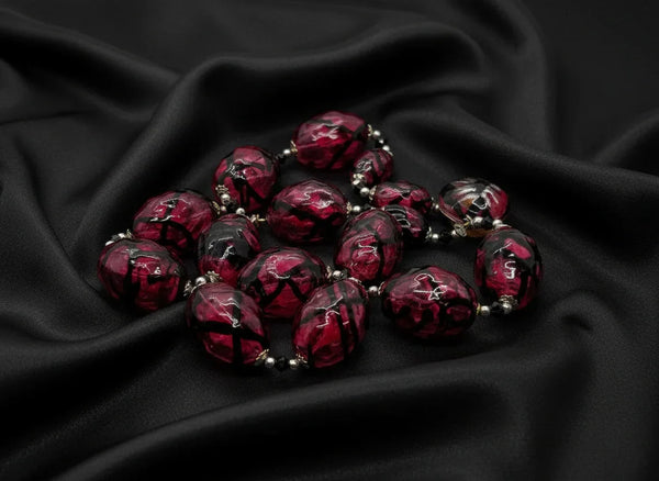 Express your unique style with this stunning Vintage Clear Magenta and Black Striped Blown Glass Beads Necklace. Its cool and smooth touch will captivate your senses, while the mesmerizing dark swirls add a touch of mystery and intrigue.