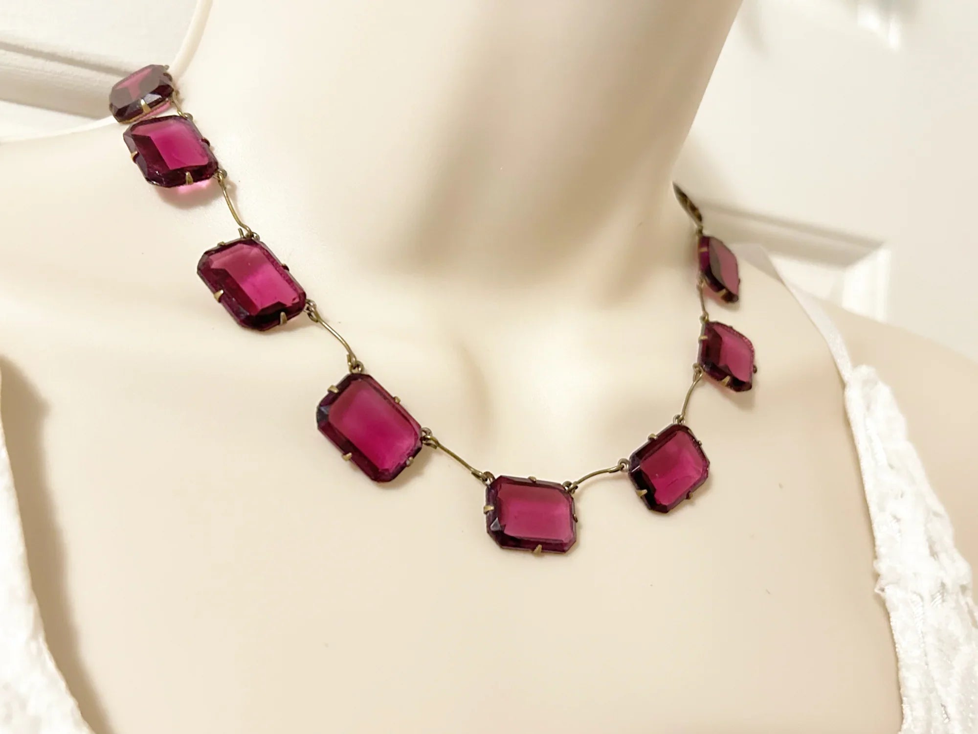 Admire the timeless beauty of our Graceful Vintage Czech Violet Clear Stones Necklace. Handcrafted with thirteen emerald cut purple clear stones encased in intricately detailed frames, this elegant necklace is a true work of art. With a length of approximately 15", it is a delicate and sophisticated addition to any outfit. Experience luxury and exclusivity with this exquisite piece, in immaculate condition.