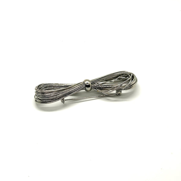 A silver-toned multi-strand wire bow brooch, featuring an infinity-shaped loop silhouette cinched with a smooth central band, displayed against a plain white background.