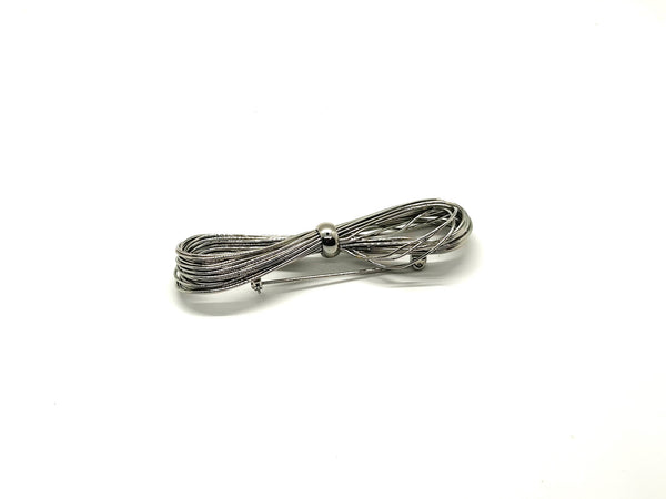A silver-toned multi-strand wire bow brooch, featuring an infinity-shaped loop silhouette cinched with a smooth central band, displayed against a plain white background.