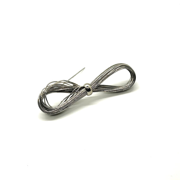 A silver-toned multi-strand wire bow brooch, featuring an infinity-shaped loop silhouette cinched with a smooth central band, displayed against a plain white background.