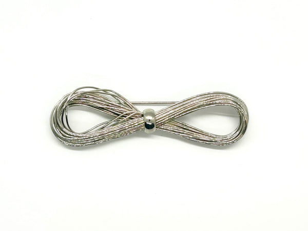 A silver-toned multi-strand wire bow brooch, featuring an infinity-shaped loop silhouette cinched with a smooth central band, displayed against a plain white background.