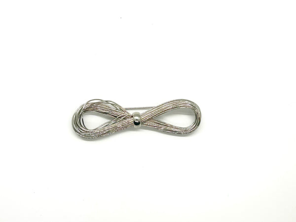 A silver-toned multi-strand wire bow brooch, featuring an infinity-shaped loop silhouette cinched with a smooth central band, displayed against a plain white background.
